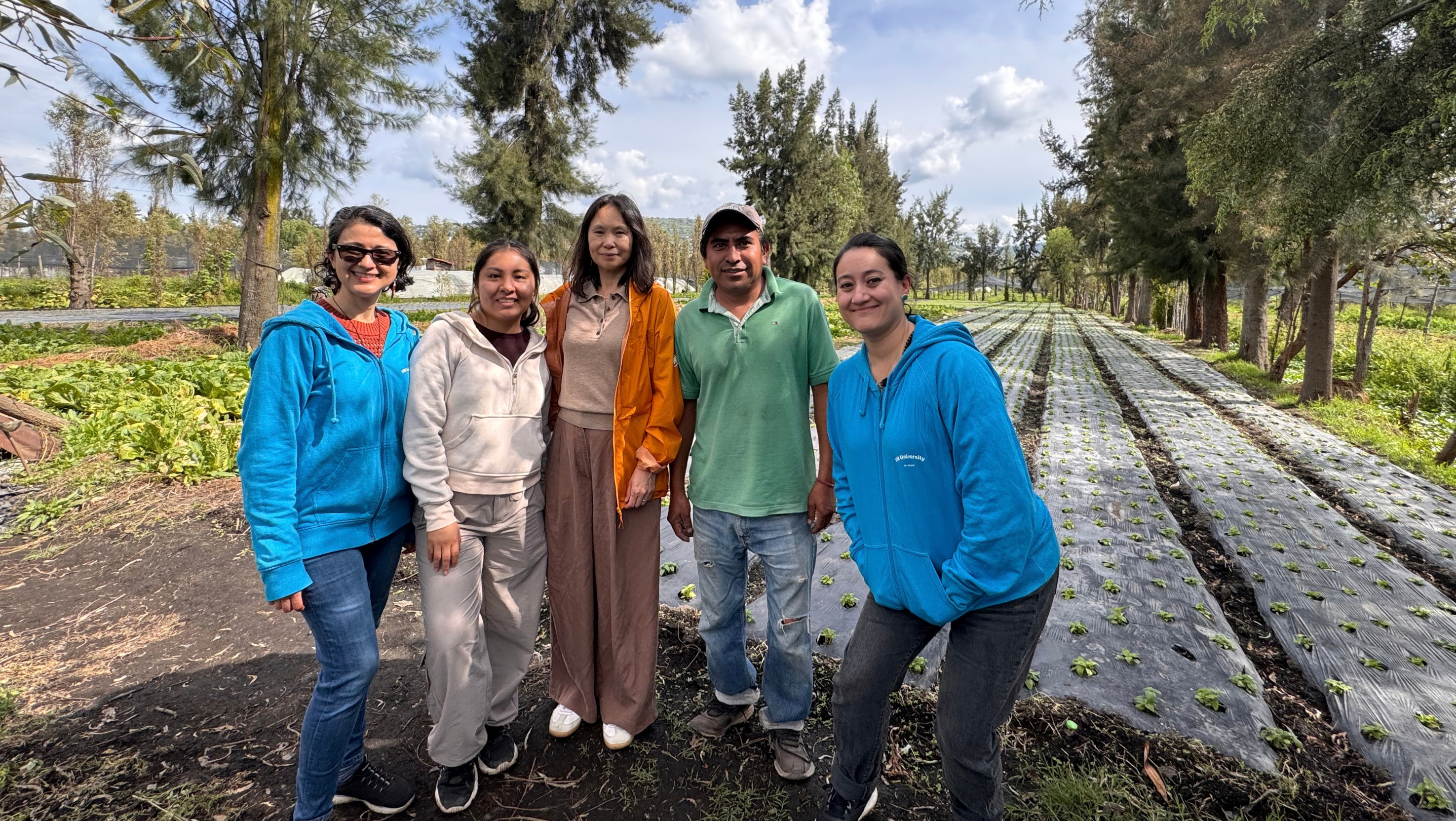 four women and a man in an agricultural field.