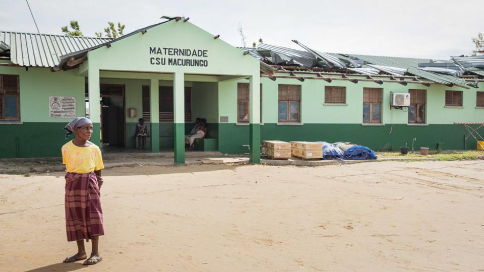 A woman stands in front of a maternity clinic that was heavily damaged by Cyclone Idai in Mozambique.