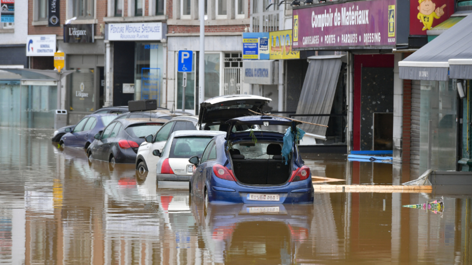 A row of cars flooded in front of a row of stores in Belgium