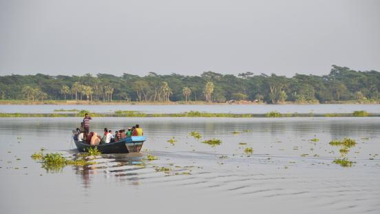 People crossing a river on a small boat in Bangladesh.