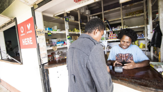 A storekeeper and customer looking at a credit card reader