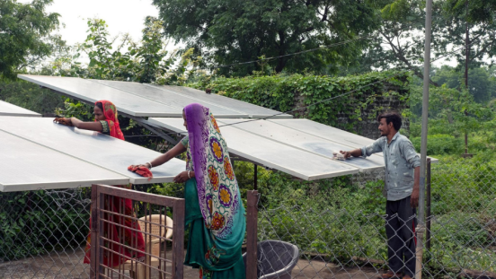 Two women and one man wiping dust off of solar energy panels