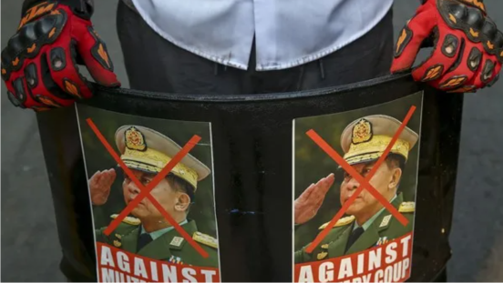 An anti-coup protester displays defaced images of commander-in-chief Gen. Min Aung Hlaing in Mandalay, Myanmar, March 3, 2021.