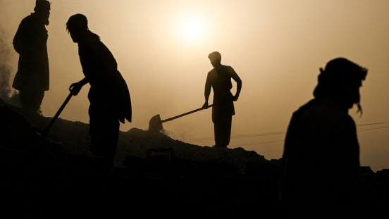 Silhouettes of people working with shovels under the burning sun