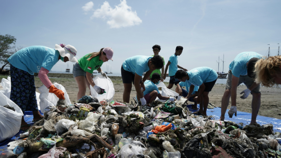 Clean-up groups sort through plastic on a beach. 