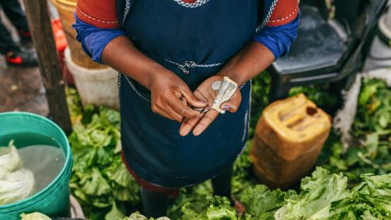 A vegetable vendor counts money at Fajardo Market in Maputo, Mozambique.
