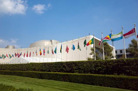 UN United Nations general assembly building with world flags flying in front.