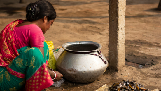 A woman sitting on the soil with a pot in front of her