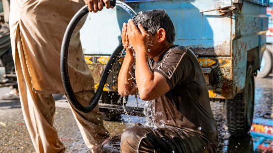 A young man is poured with water to cool during intense heat. 