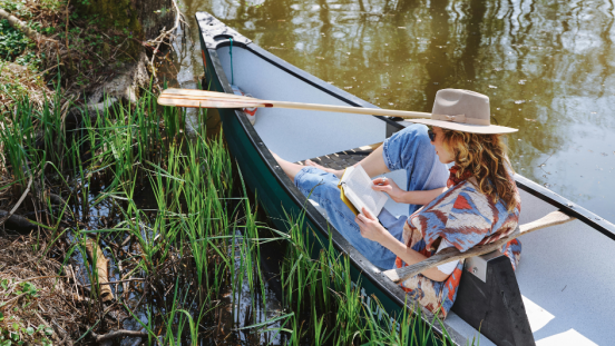 A women reads while sitting in a canoe.