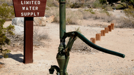 A groundwater pump in front of a sign that says limited water is available.