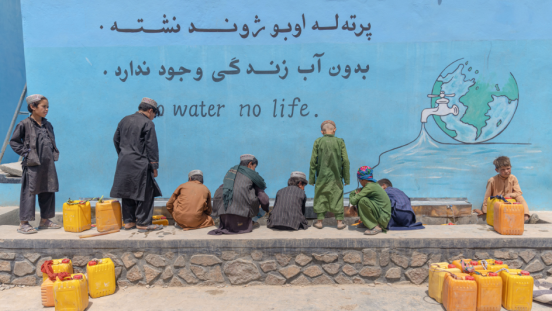 Kids fill containers with groundwater. 