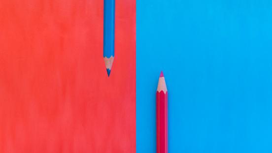 Red and blue pencils with matching colored backgrounds, showing contrast and symmetry.