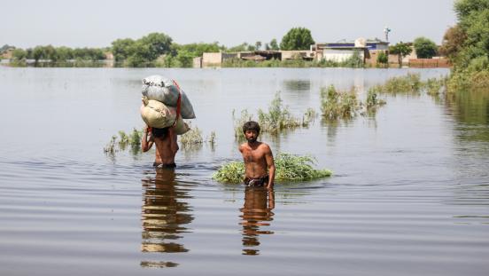 Two men walk through floodwaters in Pakistan.