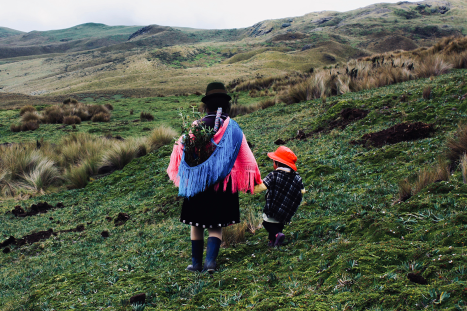 A mother and child walk through the grass in Guangaje, Ecuador, after the blessing of a water spring.