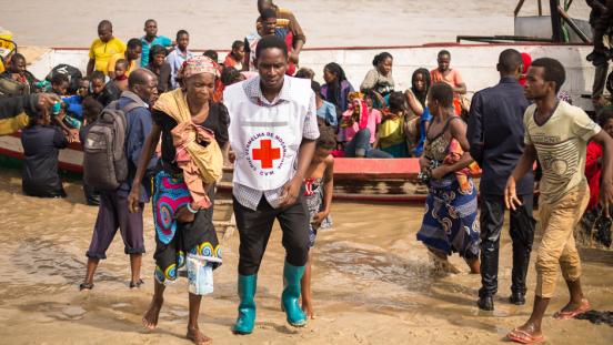 Evacuees are escorted from a boat after flooding and destruction from Cyclone Idai in Mozambique.