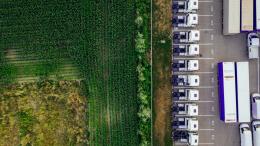 Aerial view of trucks in parking lot next to agricultural field