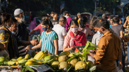 Women and men in masks at a fruit market