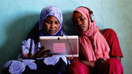 Two girls looking at a tablet device and studying