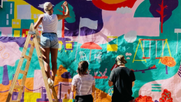 Artists paint a mural on a community wall. 
