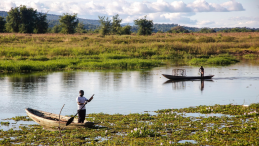 Two men in wooden boats on a river in Zambia
