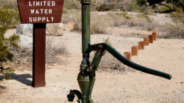 A groundwater pump in front of a sign that says limited water is available.