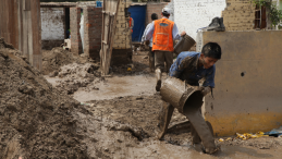 A kid poors buckets of mud following a landslide in Peru. 