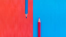 Red and blue pencils with matching colored backgrounds, showing contrast and symmetry.