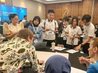 Participants gather around a table during a roundtable session, reviewing the session guide and discussing ideas in a conference room.