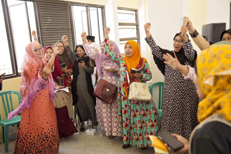 Women cheer at a community gathering to discuss peacebuilding in Pesantren Annuqqayah.