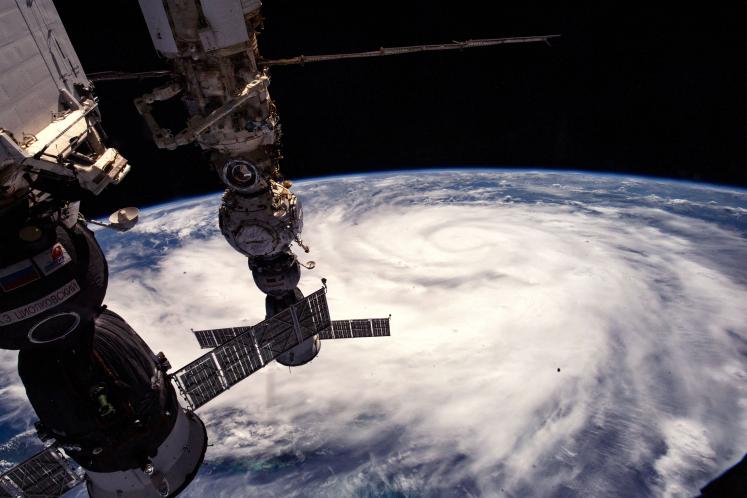 The International Space Station orbits above earth with a hurricane in view. 