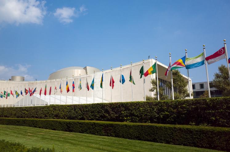 UN United Nations general assembly building with world flags flying in front.
