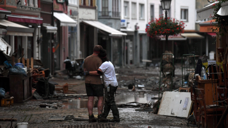 A couple standing in front of damages after the Western Europe floods in 2021