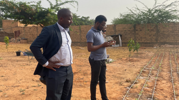 Two men look at an irrigation system in a field in Africa.