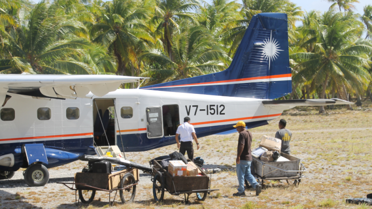 People and their luggage boarding a small plane on a strip of sand