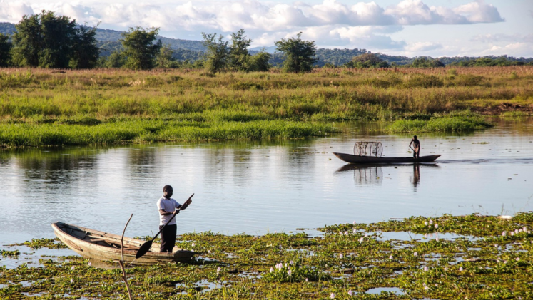 Two men in wooden boats on a river in Zambia