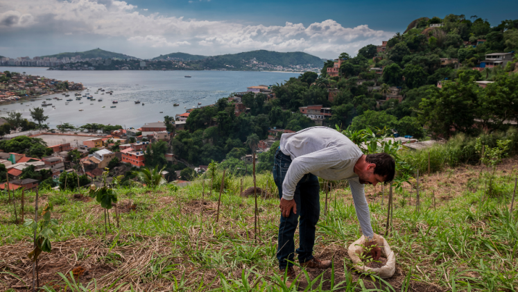A man working in a field with the ocean in the background