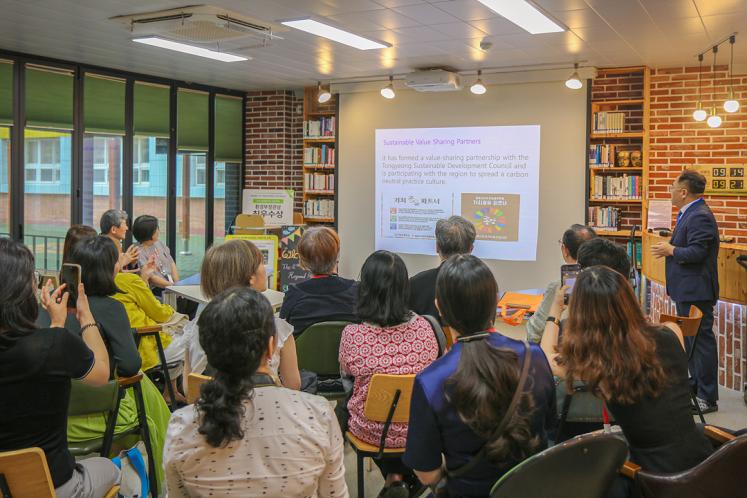 A group of people listening attentively to a man with a slide presentation.