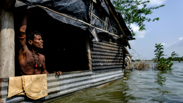 A man looks out of a window from his flooded home in Sundarbans, West Bengal. 
