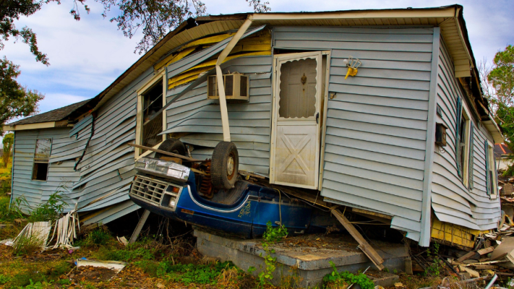 A car is sandwiched under a house after a storm. 