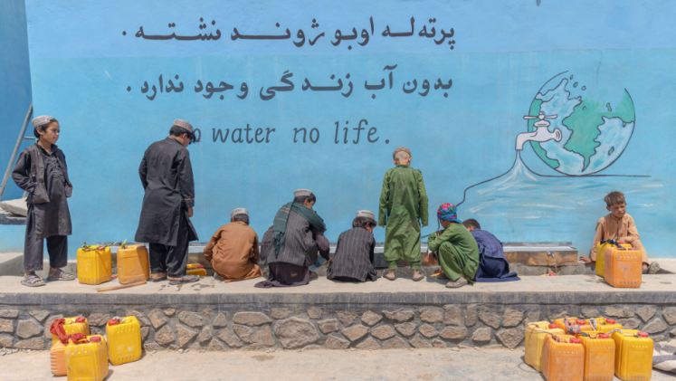 Kids fill containers with groundwater. 