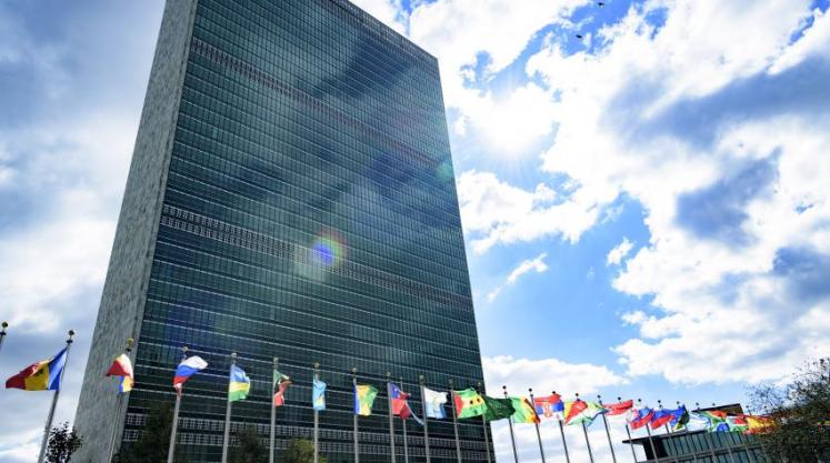 Secretariat building with flags of Member States in the foreground, at UN Headquarters.