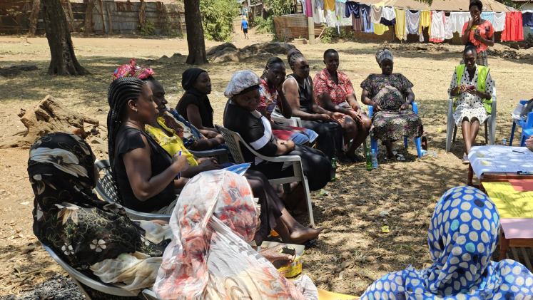 A group of women sit outside in a circle. 