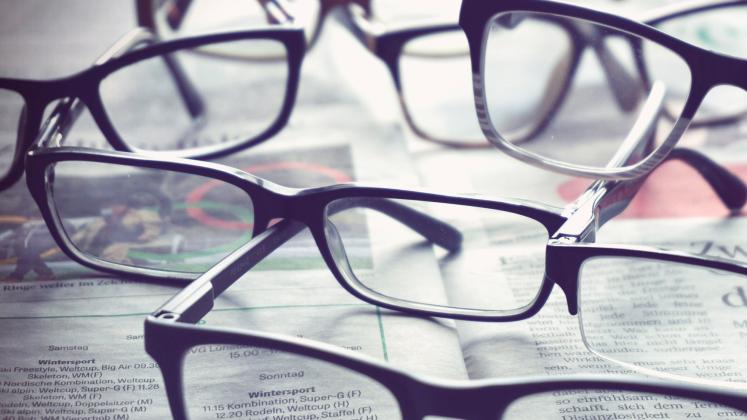 A variety of eyeglasses scattered on newspapers