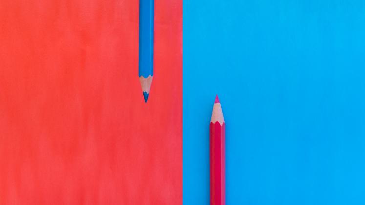 Red and blue pencils with matching colored backgrounds, showing contrast and symmetry.