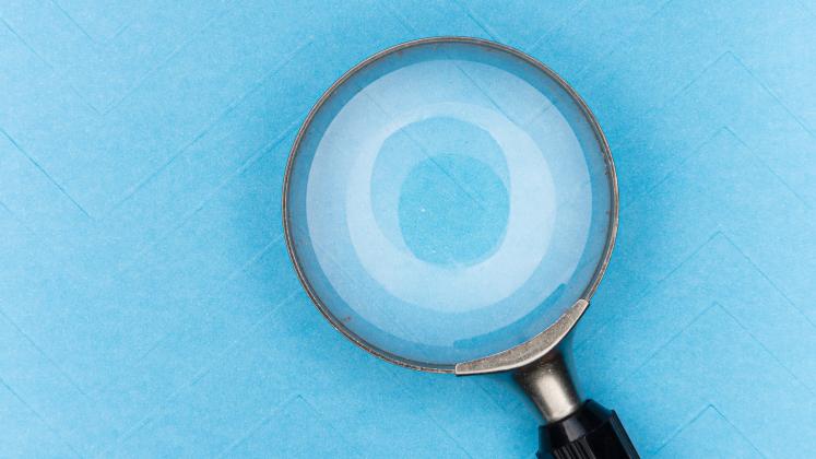 A magnifying glass on blue paper