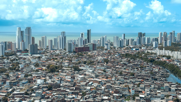 Aerial view of the urban landscape of Recife, Brazil with a skyline of modern buildings against a blue sky with some clouds here and there. 