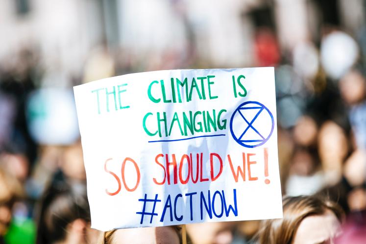 Person holding a sign that reads "The Climate is Changing".