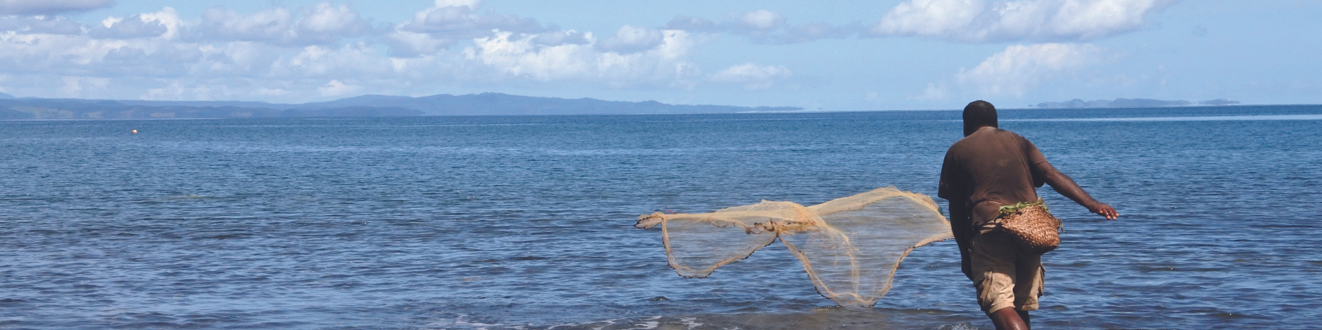 A man throwing a fishing net into the ocean